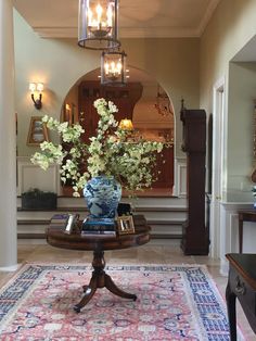 a vase with flowers sitting on top of a table in front of a mirror and doorway