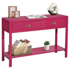 a pink console table with two drawers and a book shelf on top, next to a potted plant