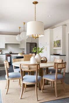 a dining room table with blue chairs and a white chandelier hanging from the ceiling