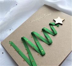 a green christmas card with gold stars and ribbon around it on top of a white table cloth