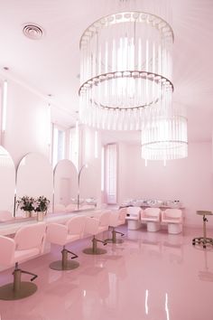 the interior of a salon with pink chairs and chandelier