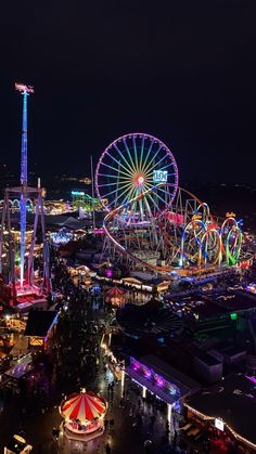 an aerial view of a carnival at night with ferris wheel and rides in the background