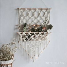 a white macrame hanging on the wall next to a potted plant with succulents in it