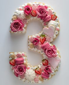 the letter e is made up of cookies and decorated with pink flowers, hearts, and other things