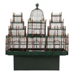 a bird cage with several birds in it sitting on top of a green stand next to a white wall