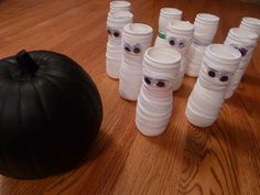 there are many plastic cups sitting on the floor next to a black ball and pumpkin