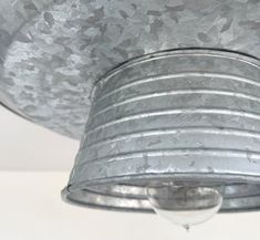 an old tin can light fixture hanging from the ceiling in a room with white walls