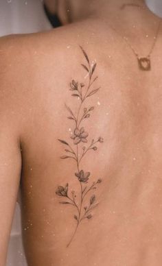 the back of a woman's shoulder with a flower tattoo on her left side