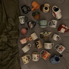 there are many mugs on the bed together