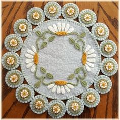 a white doily with daisies and leaves in the center on a wooden table