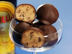 a glass filled with chocolate covered donuts next to a bottle of wine and a can