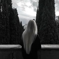 a woman with long white hair looking out over trees