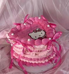 a hello kitty cake with pink icing and bows on it's top tier