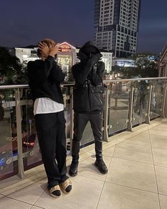 two people standing next to each other in front of a cityscape at night