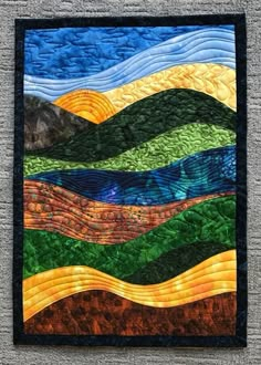 a quilted wall hanging on the side of a gray wall with mountains in the background