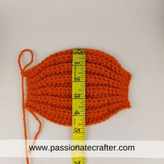 an orange crochet hat with a measuring tape