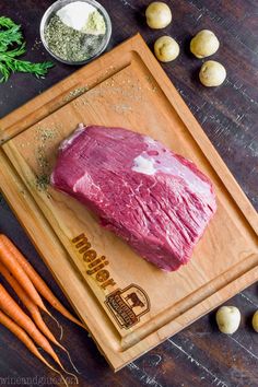 raw meat on cutting board with carrots and garlic