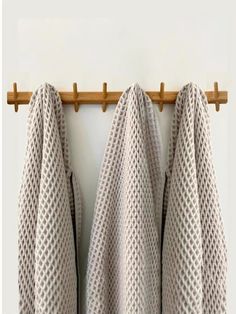 two white towels hanging on a wooden rack