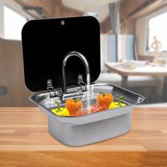 a kitchen sink filled with lots of fruit and vegetables next to a black square box