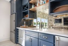 a kitchen with blue cabinets and stainless steel appliances in the center, along with marble counter tops