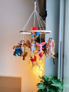 winnie the pooh and friends mobile hanging from a light fixture next to a potted plant