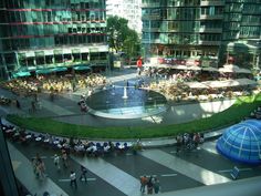 an aerial view of a city square with people walking and sitting in the center, surrounded by tall buildings