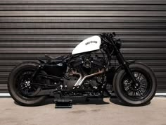 a black and white motorcycle parked in front of a garage door