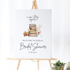 a welcome sign for a bridal shower with books and flowers in the background on an easel