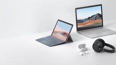 two laptops and headphones are sitting on a white surface next to each other