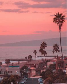 cars are parked on the side of the road near the beach as the sun sets