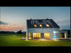 a house with solar panels on the roof and windows lit up at night in front of it