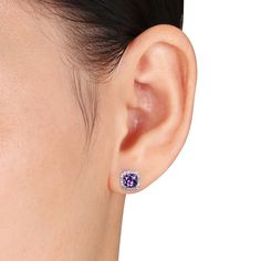 She's certain to adore these captivating gemstone and diamond earrings. Fashioned in 10K white gold, each earring is centered with a lovely 5.0mm cushion-cut bright purple amethyst, glittering in a classic four-prong setting. A halo frame of shimmering diamonds wraps the center stones in a sparkling embrace, adding even more brilliance. Perfect for the February-born birthday girl, these stud earrings captivate with 1/10 ct. t.w. of diamonds and a bright polished shine. The earrings secure comfor February Born, Diamond Halo Earrings, Halo Diamond Earrings, Diamond Frame, Peoples Jewellers, Halo Earrings, Bright Purple, Diamond Stud Earrings, Diamond Stud