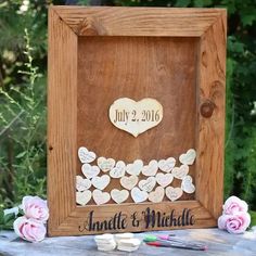 a wooden frame with hearts on it next to pink flowers and greenery in the background