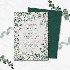 an elegant wedding card with green and white flowers on the front, surrounded by greenery