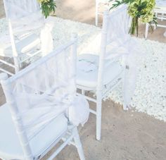 two white chairs are set up for a wedding ceremony