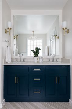 a bathroom vanity with two sinks and large mirror above it in a white walled room