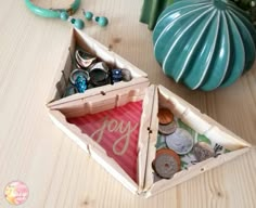 two wooden boxes filled with different types of buttons and beads on a table next to a vase