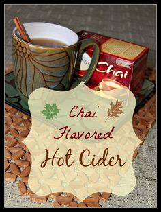 a cup of hot cider next to some crackers on a tray with a sign that says chai flavored hot cider