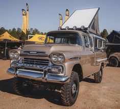 an old truck with a camper attached to it's hood parked in a lot