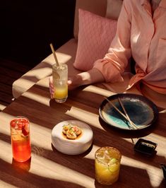 a woman sitting at a table with food and drinks