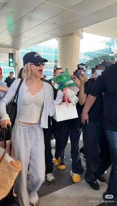 a woman is walking through an airport with her hand in her pocket and people behind her