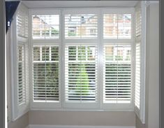 an empty room with white shutters on the windows