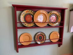 a red shelf with plates on top of it and two shelves above the plate rack