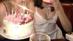 two women sitting next to each other at a table with a cake in front of them