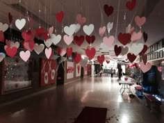 valentine's day decorations hang from the ceiling in an empty room with people walking by