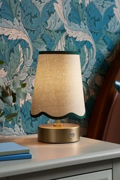 a lamp sitting on top of a table next to a blue and white wallpaper