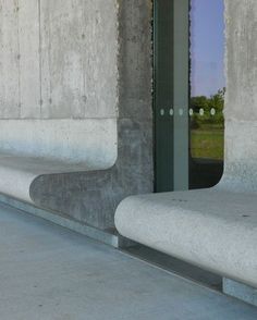 two cement benches sitting next to each other in front of a building with glass doors