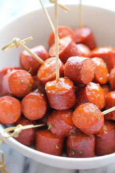 a white bowl filled with cooked carrots and skewers on toothpicks