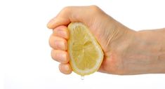 a person's hand holding a half eaten lemon