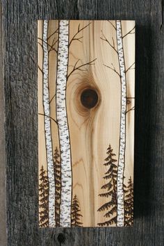 a wooden plaque with trees painted on it